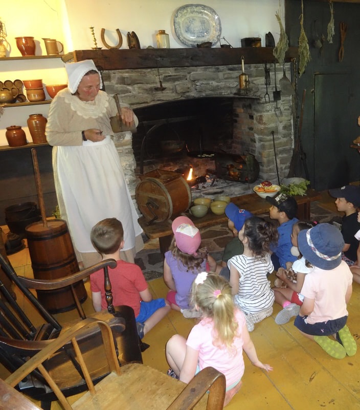 Mrs Thomas in historical clothing cooking over the fire