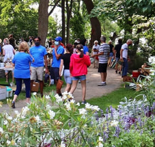 people milling about in front of tables in a park yard sale