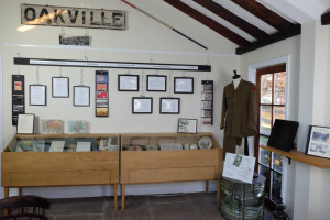 exhibit of World war one with hanging uniform and photos on a timeline above a case with exhibits