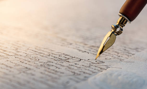 Close up shot of Quill pen on paper with calligraphy writing