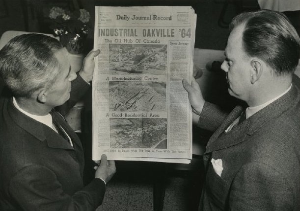 Two men holding up newspaper with headline industrial Oakville 64